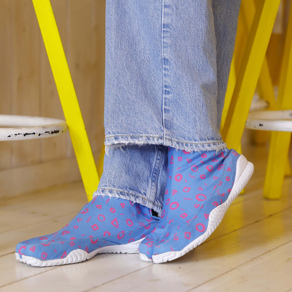 Close-up of MARU SANKAKU SHIKAKU tabi socks featuring a split-toe design and colorful geometric patterns, worn with denim pants.