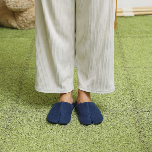 Person wearing navy PILE split-toe room shoes, standing on a grassy surface